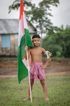 A young boy celebrates Indian Independence Day holding the national flag outdoors in Agartala.